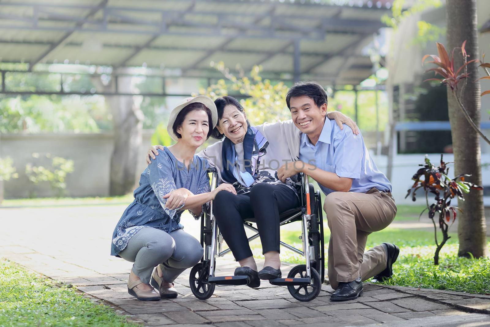 Son and daughter in law looking after elderly mother in backyard by toa55