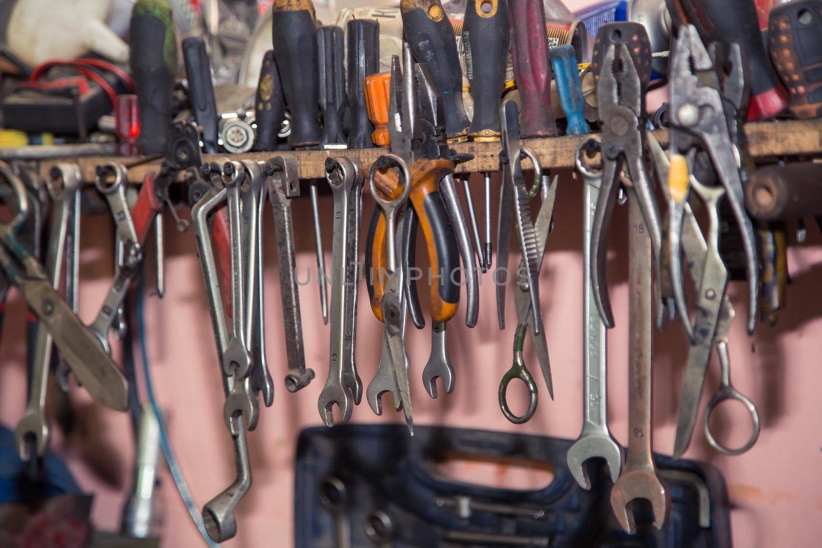 A set of wrenches, screwdrivers, pliers hang on a shelf in the workshop. In the garage are tools for repairing broken vehicle parts. Small business concept, car repair and maintenance service.