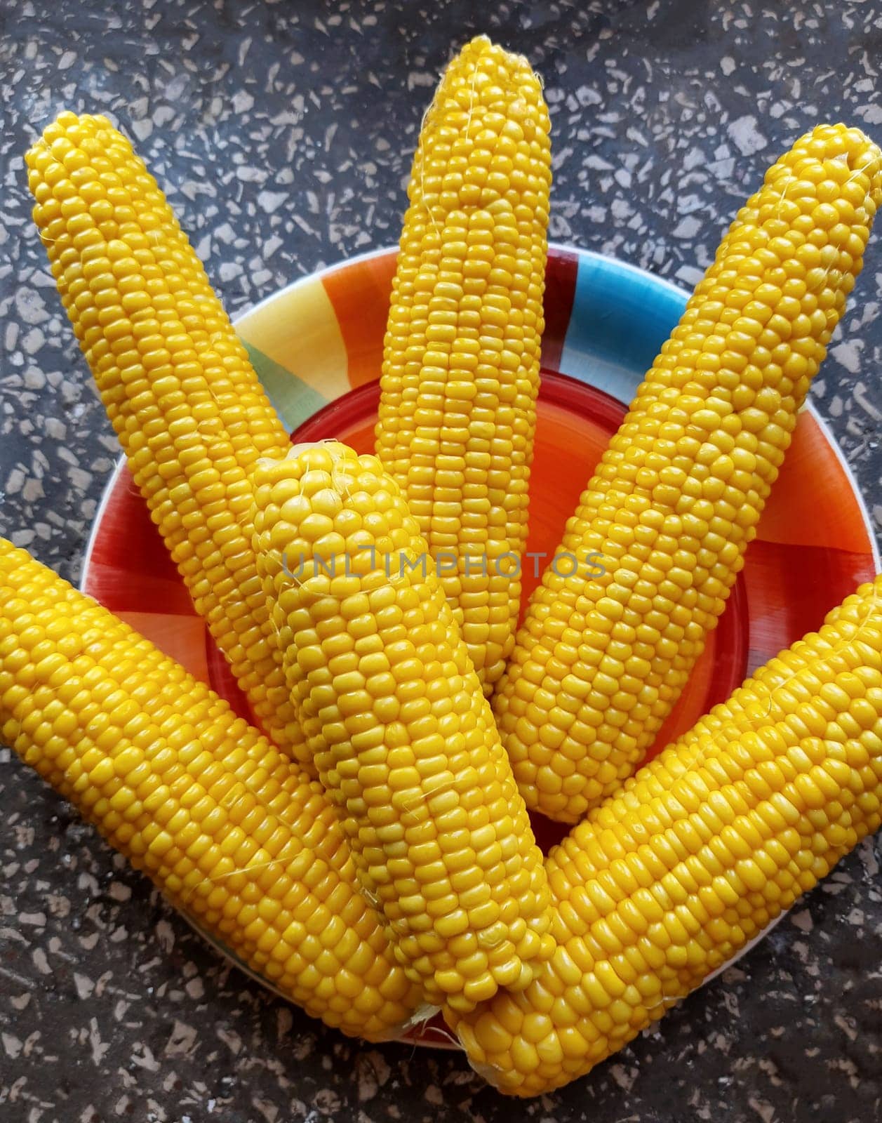 Boiled juicy yellow corn in a plate on the table close-up.