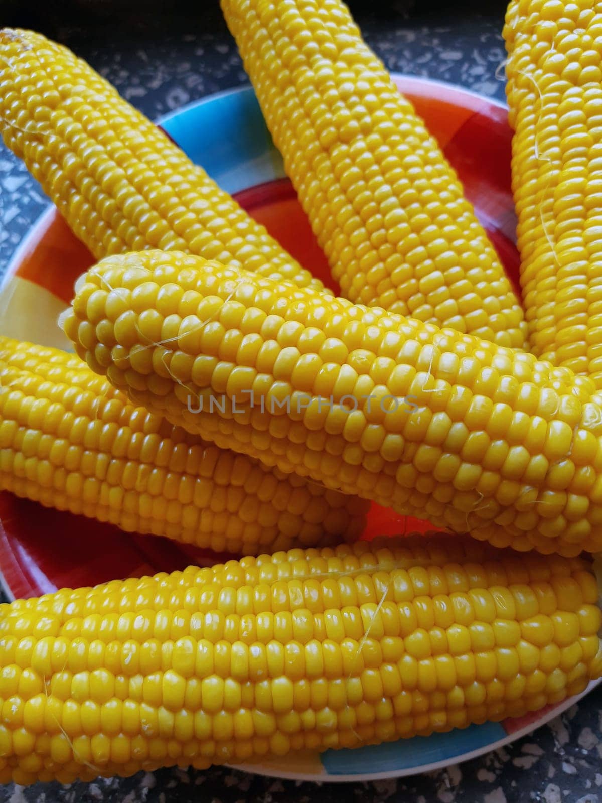 Boiled juicy yellow corn in a plate on the table close-up.