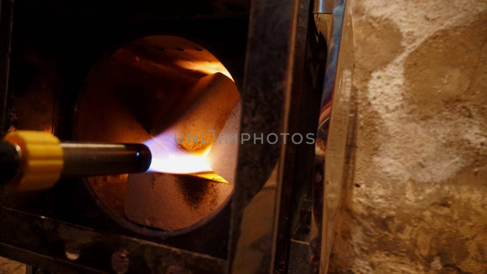 The guy lights a fire in the oven. To lay firewood. Camping stove with fuel briquettes. We make a fire with a gas burner. A smoke extraction hole is visible. The shiny walls of the furnace.