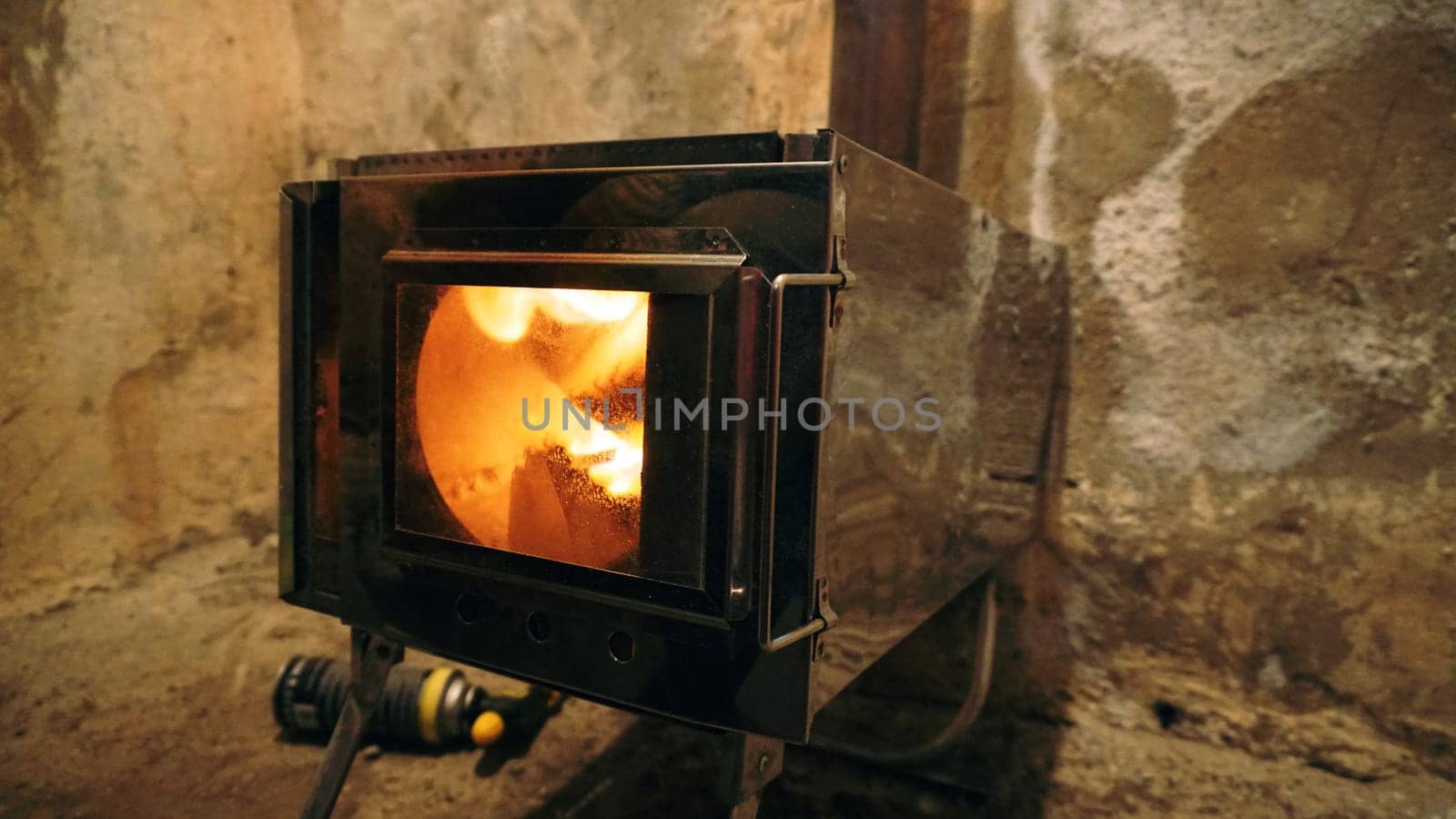 A fire in a camping stove with a glass door. by Passcal