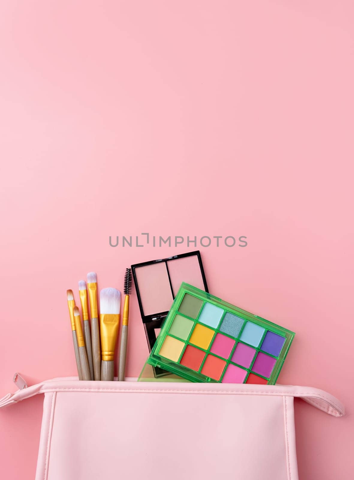 Bright summer eyeshadow palette and makeup products in pink cosmetic bag on pink background. Makeup cosmetics. Colorful colors. Place for text. Flat lay. Top view. layout