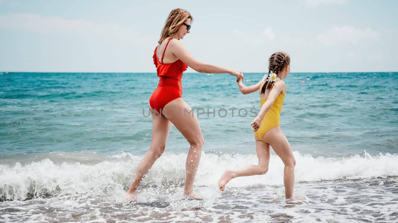 Happy loving family mother and daughter having fun together on the beach. Mum playing with her kid in holiday vacation next to the ocean - Family lifestyle and love concept.