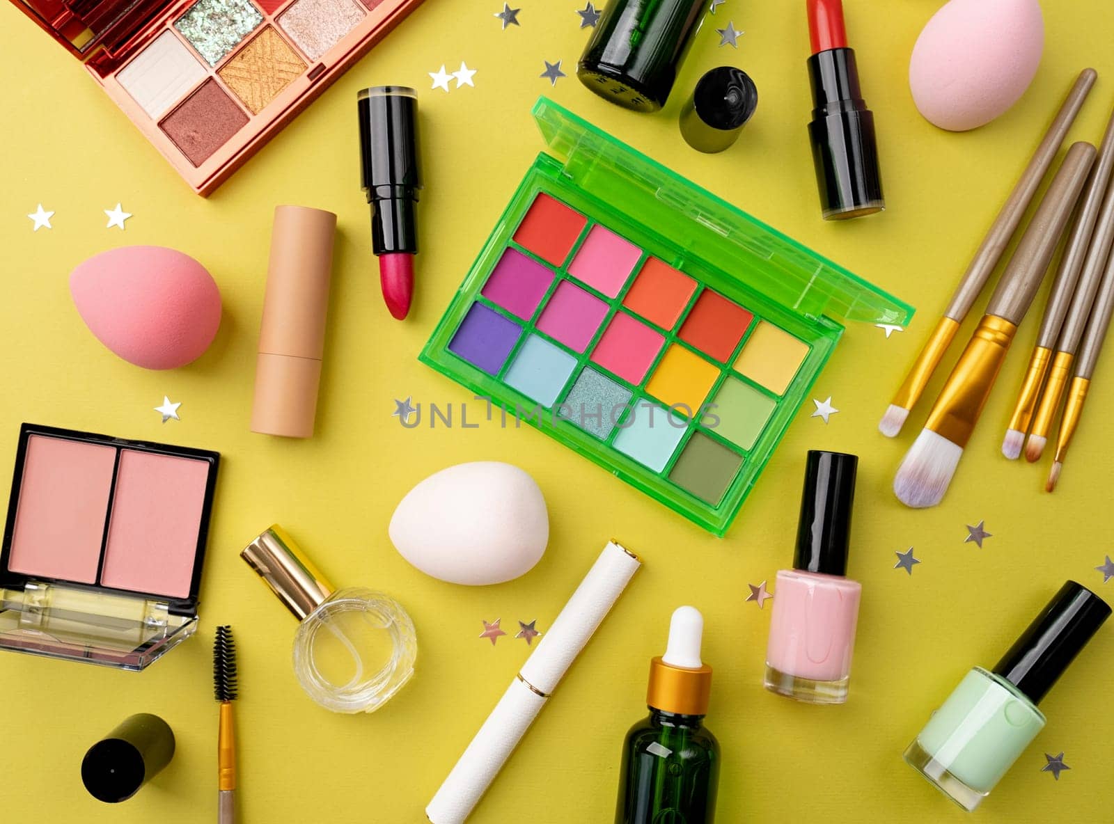 Bright summer eyeshadow palette and makeup products on green background. Makeup cosmetics. Colorful colors. Place for text. Flat lay. Top view. layout