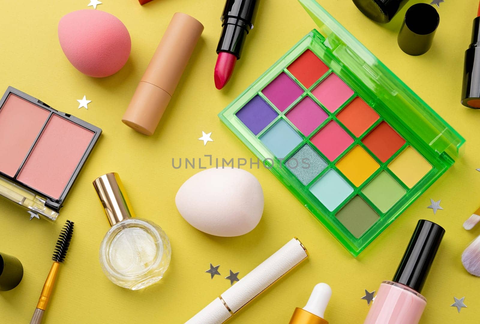 Bright summer eyeshadow palette and makeup products on green background. Makeup cosmetics. Colorful colors. Place for text. Flat lay. Top view. layout