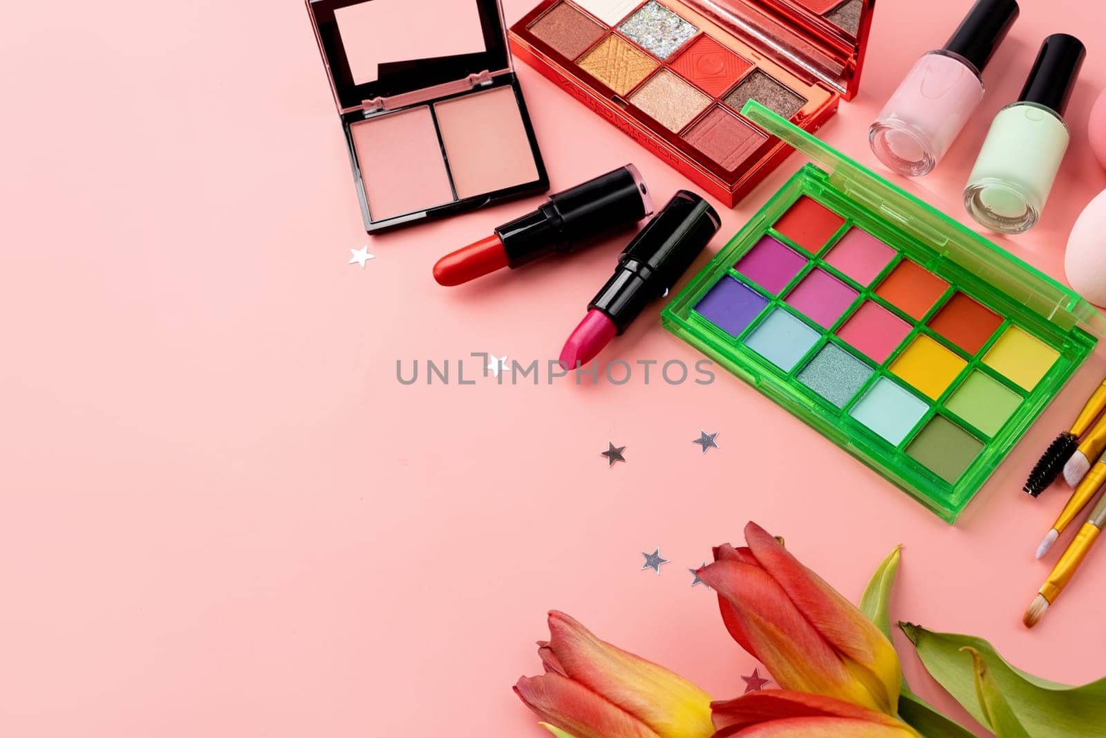 Bright summer eyeshadow palette and makeup products on pink background. Makeup cosmetics. Colorful colors. Place for text. Flat lay. Top view. layout