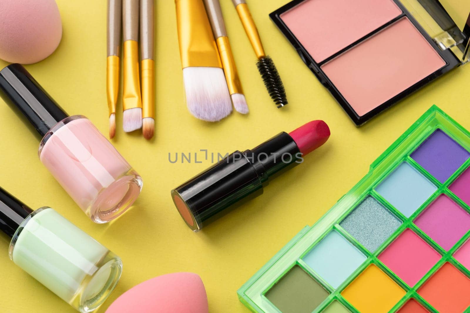 Bright summer eyeshadow palette and makeup products on green background. Makeup cosmetics. Colorful colors. Place for text. Flat lay. Top view. layout