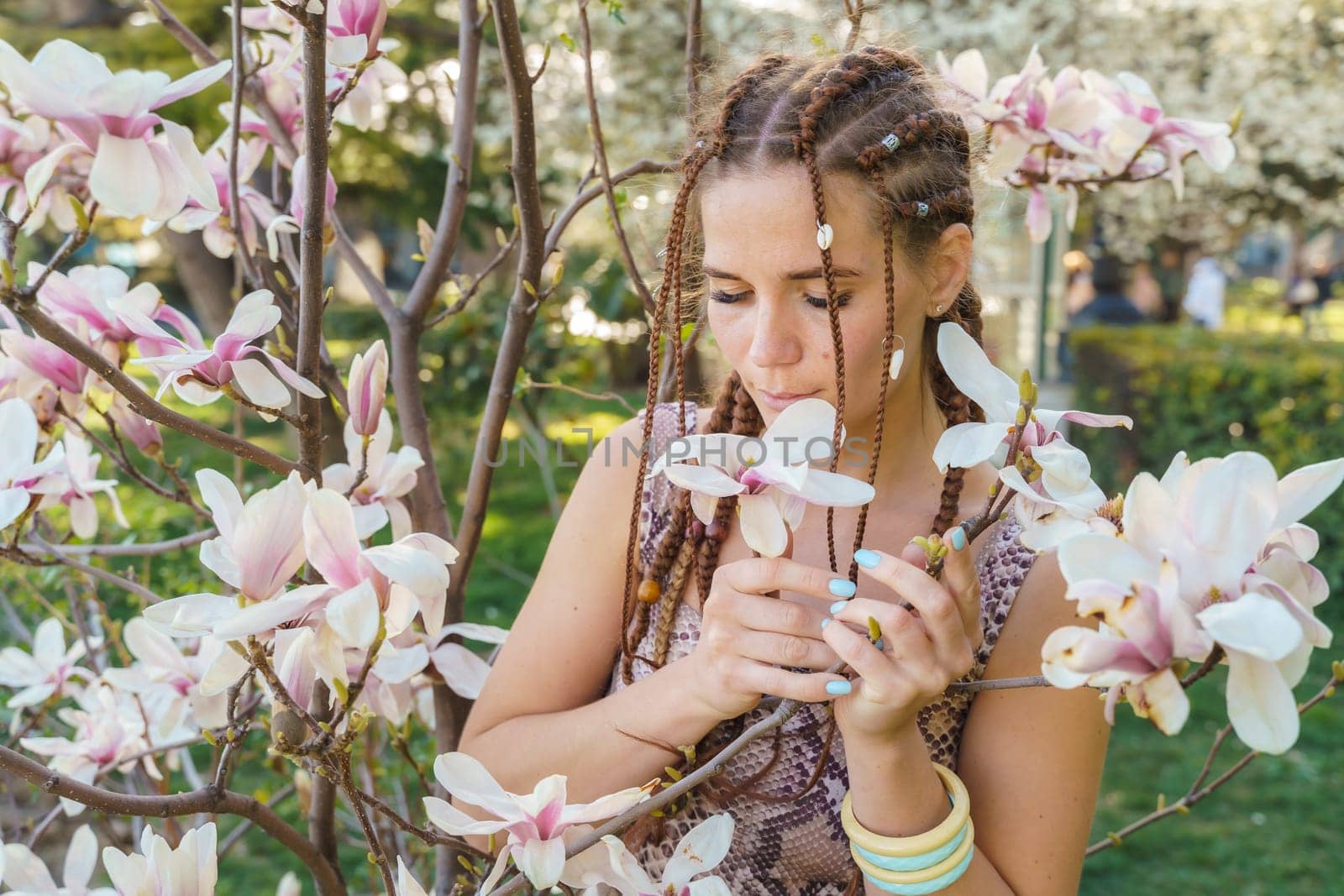 Magnolia flowers, a girl smells a blooming magnolia in the park in the sun, enjoys her vacation