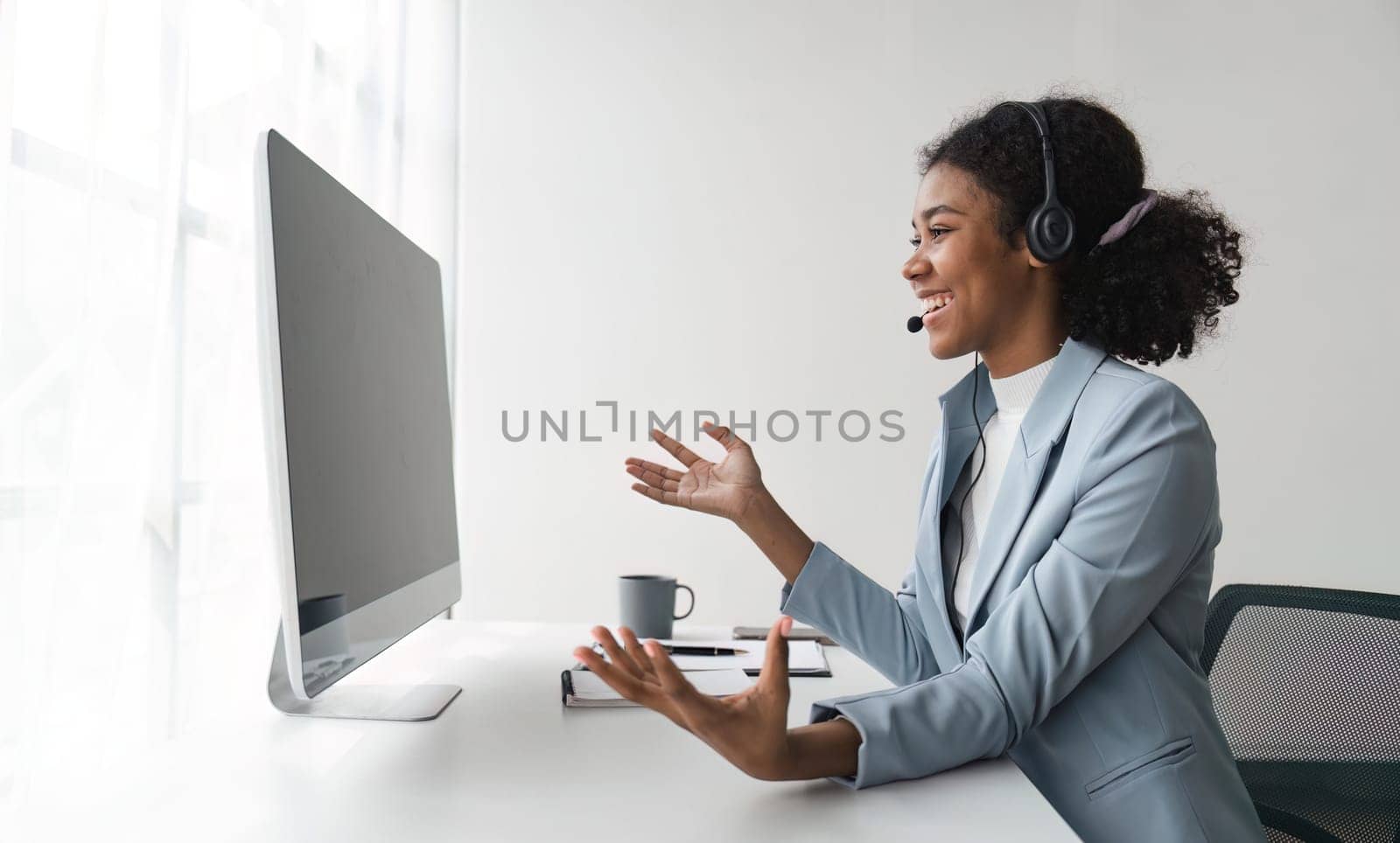 Portrait of happy smiling female customer support phone operator at workplace. Smiling beautiful African American woman working in call center.