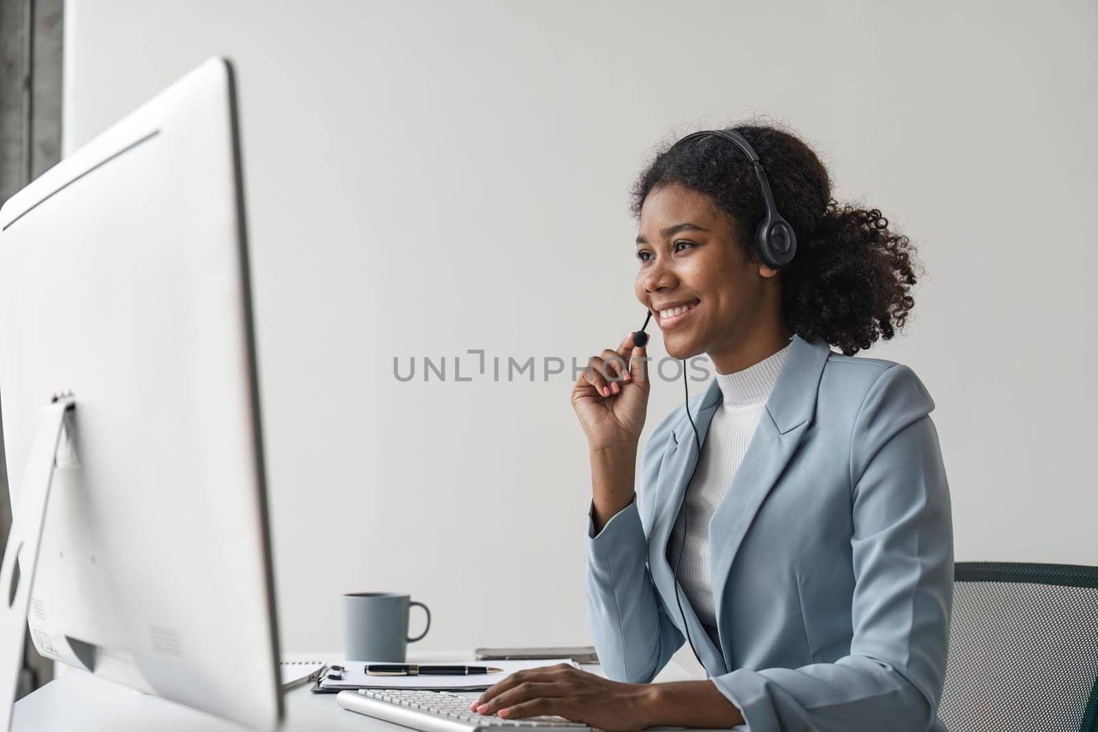 Portrait of happy smiling female customer support phone operator at workplace. Smiling beautiful African American woman working in call center.