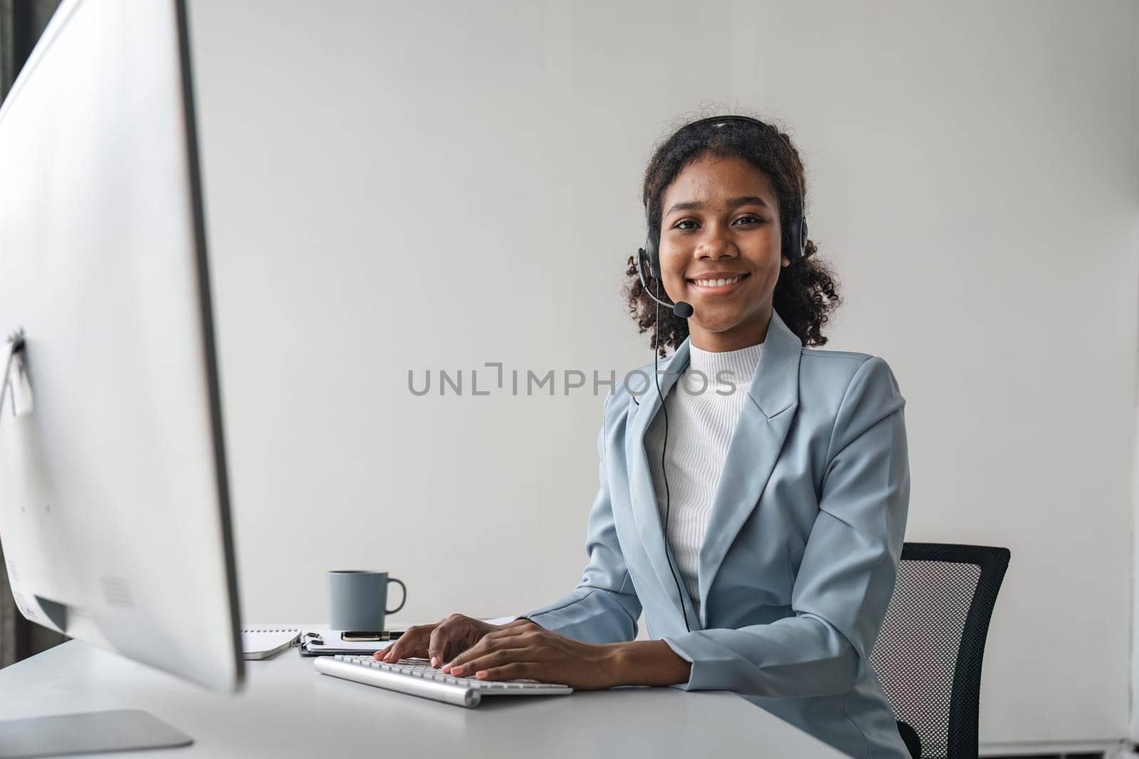 Portrait of happy smiling female customer support phone operator at workplace. Smiling beautiful African American woman working in call center.