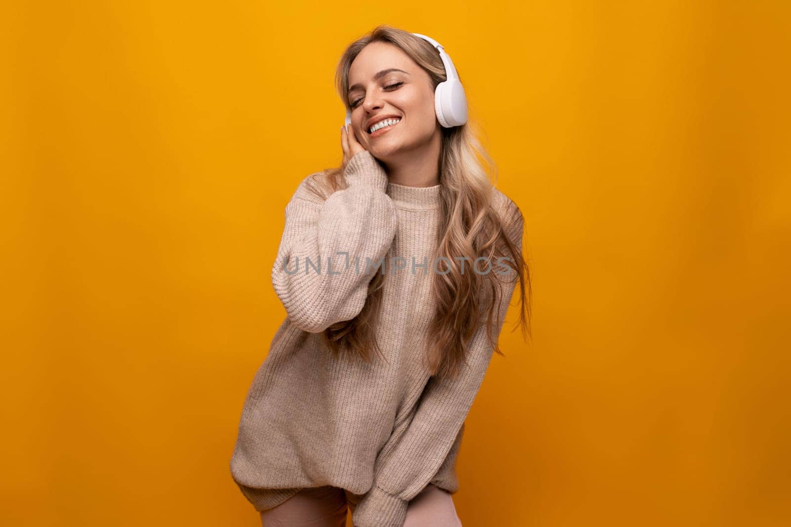 woman dancing to music in white headphones on yellow background by TRMK