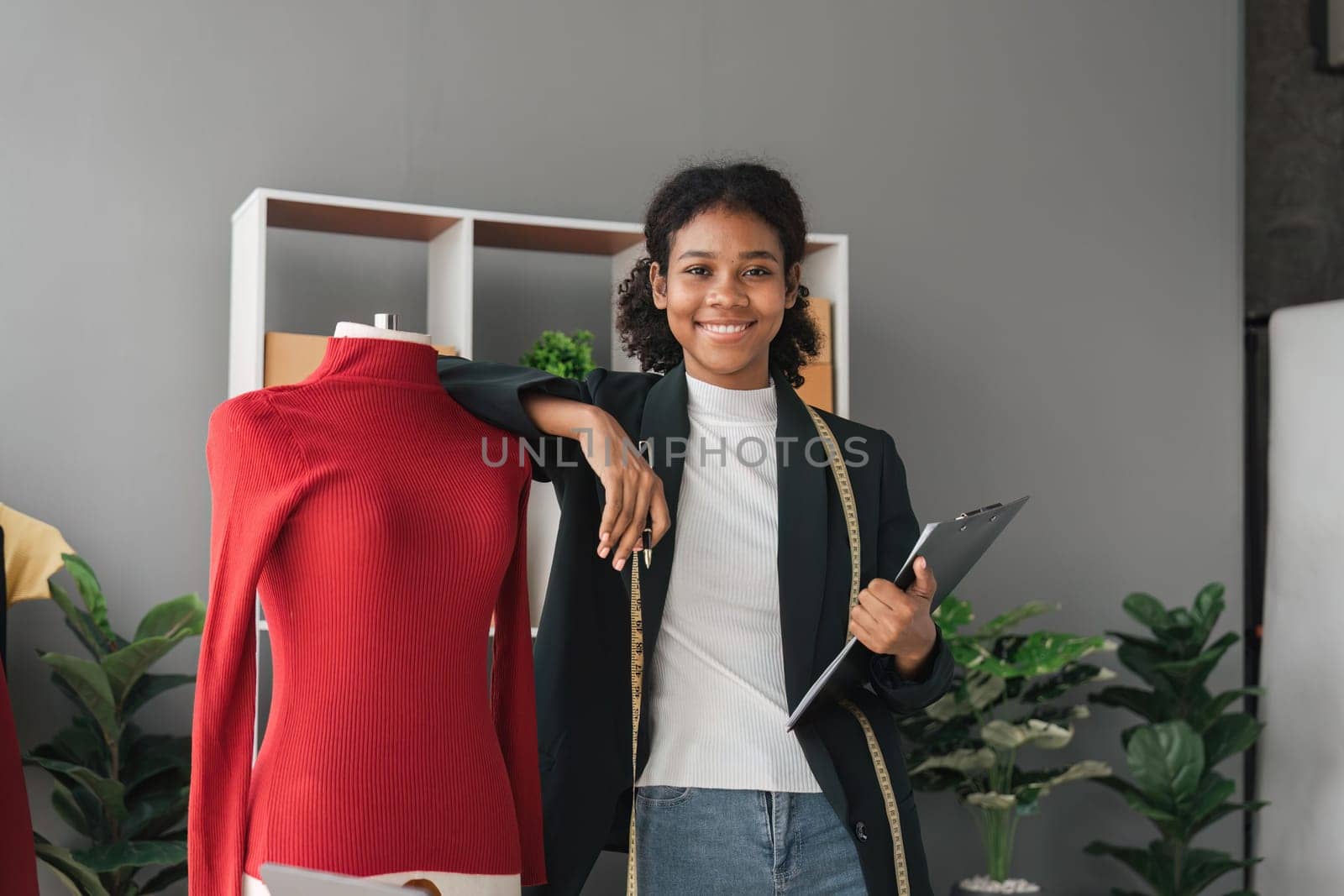 Female stylist Successful Fashion Business. Portrait of Smiling Black Designer stylish standing and working at fashion studio. Portrait of fashion designer in office. by nateemee