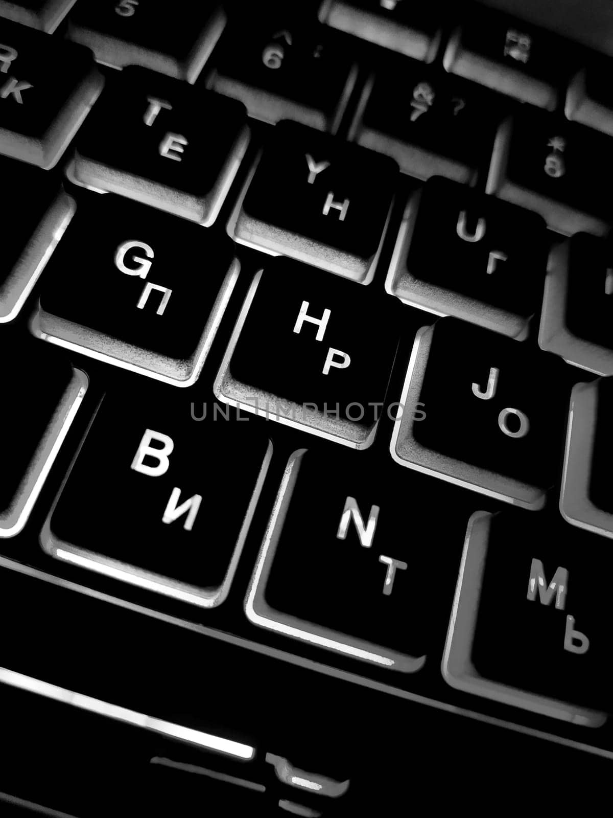 Computer keyboard black and white backlit close up.