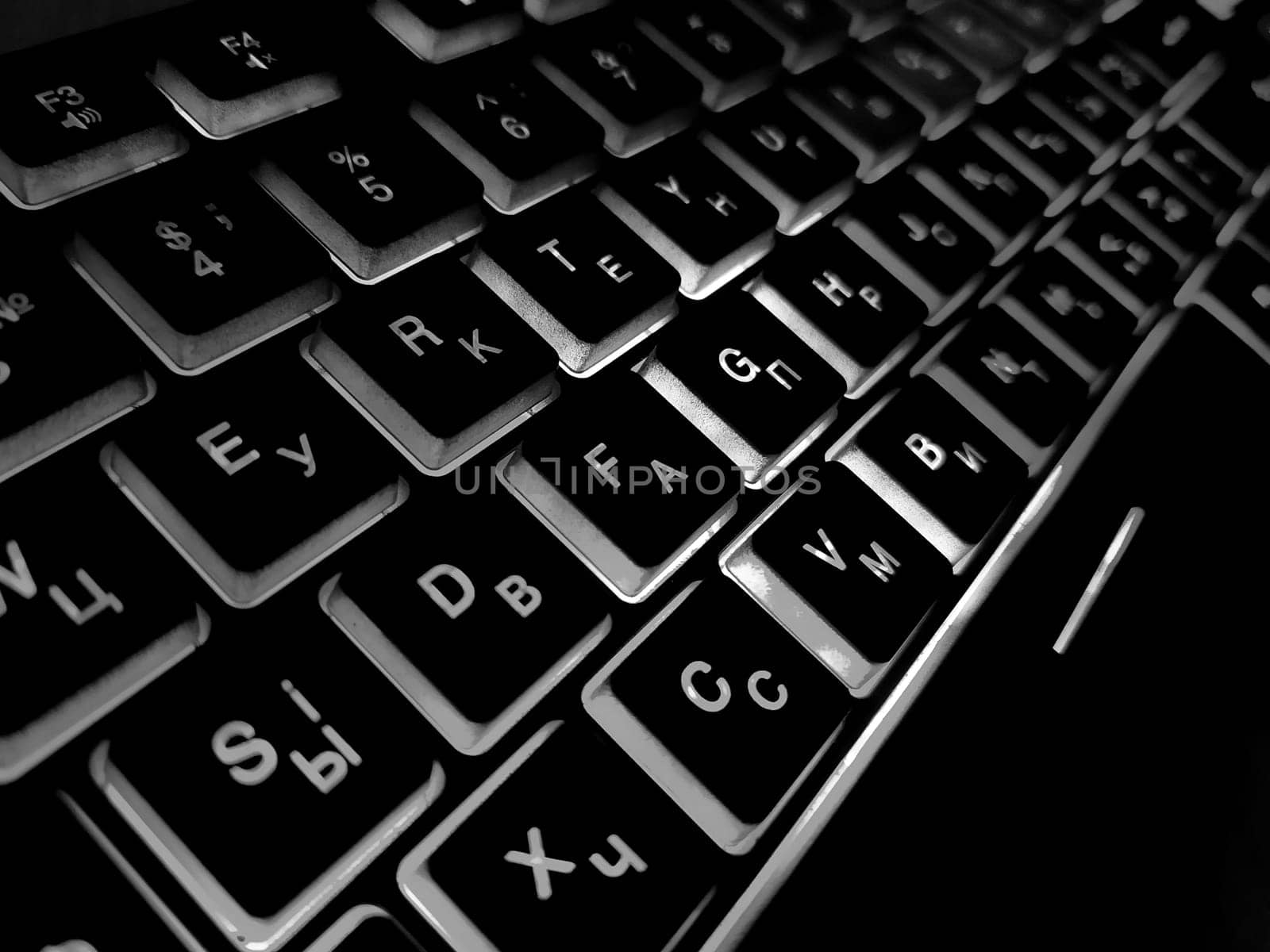 Computer keyboard black and white backlit close up.