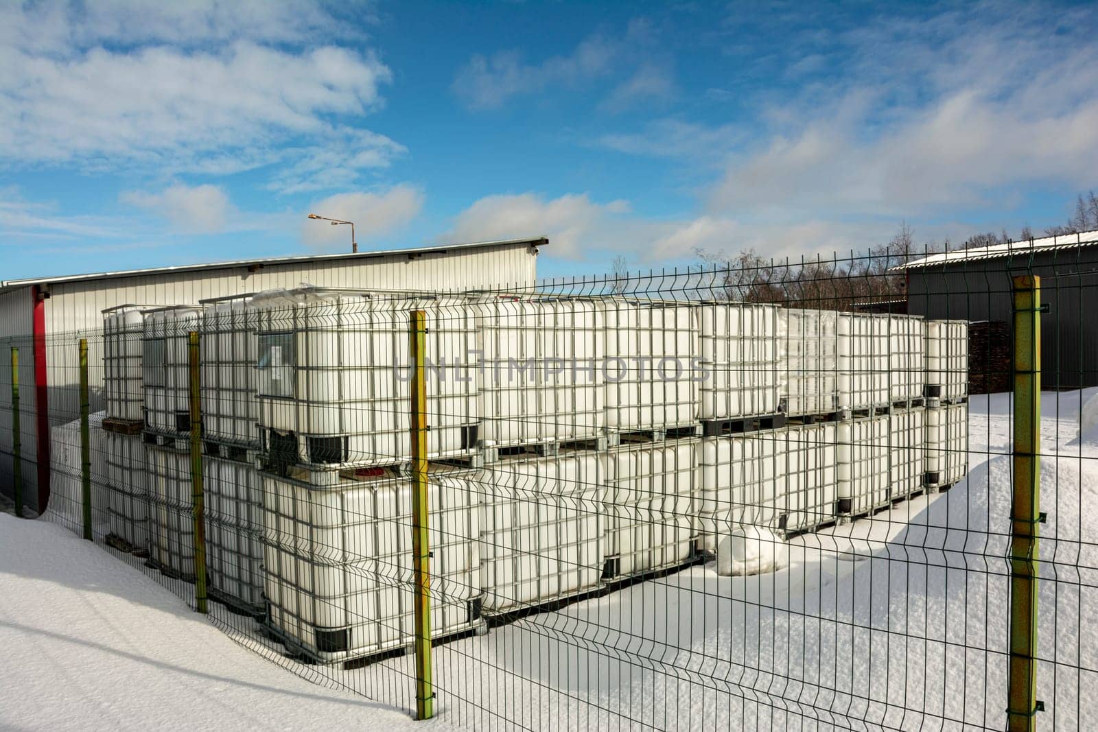 a plastic cubic water container protected by a metal grid. Plastic tanks for storage and transportation of chemical liquids.