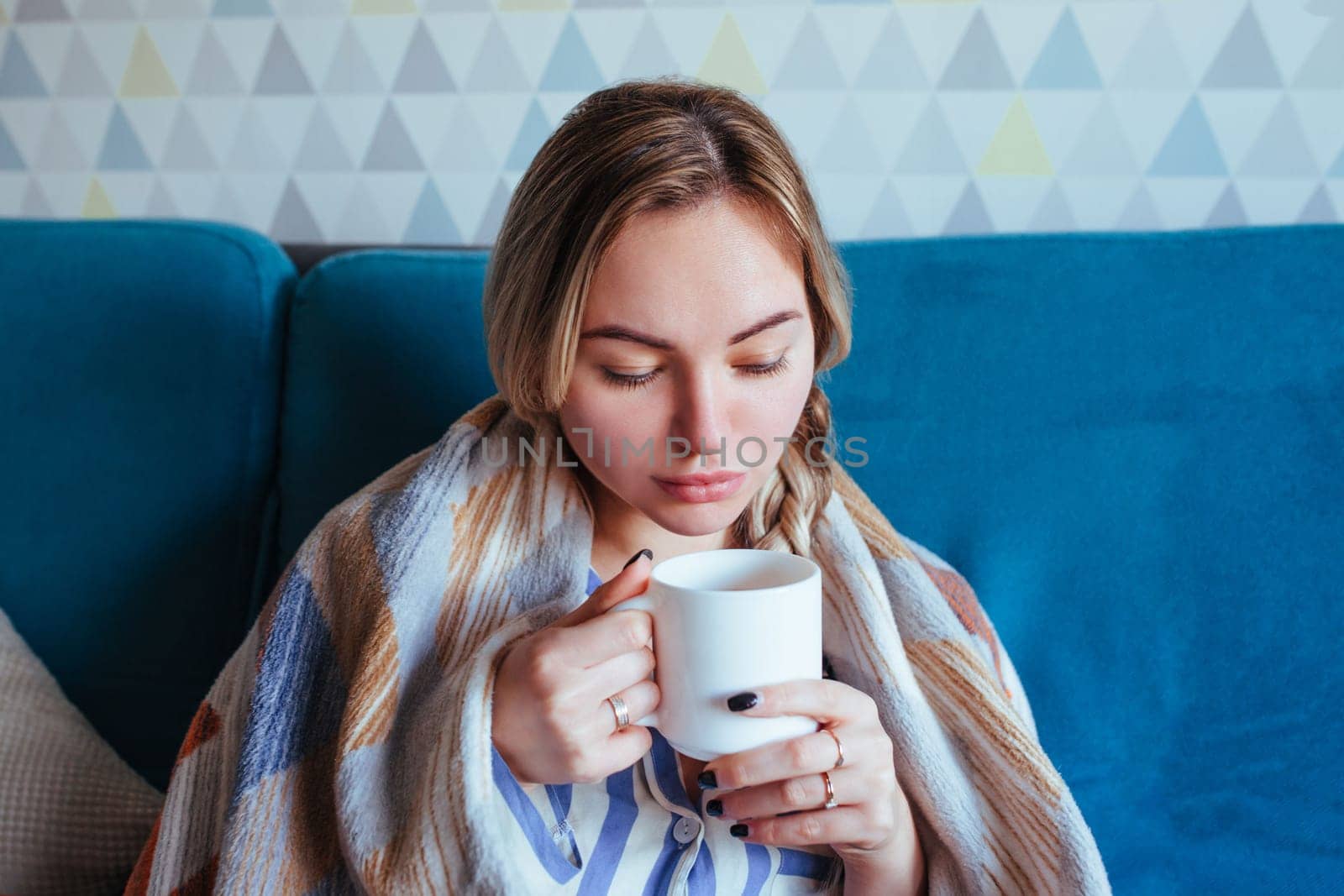 the sick girl drinks tea and wraps herself up in a blanket. treatment and panacea concept.