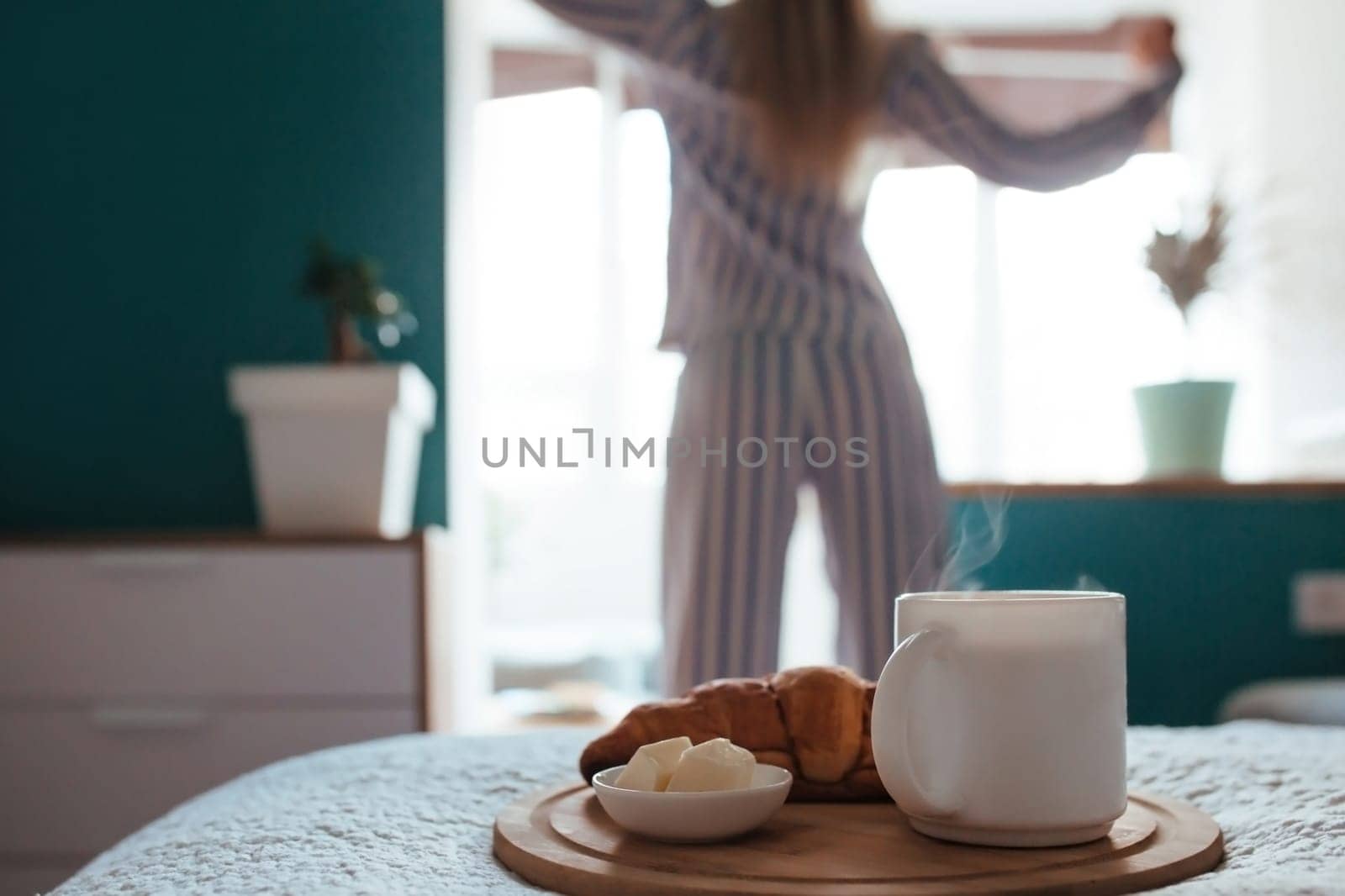 croissant and coffee in the foreground on the back of a girl in pyjamas. breakfast concept