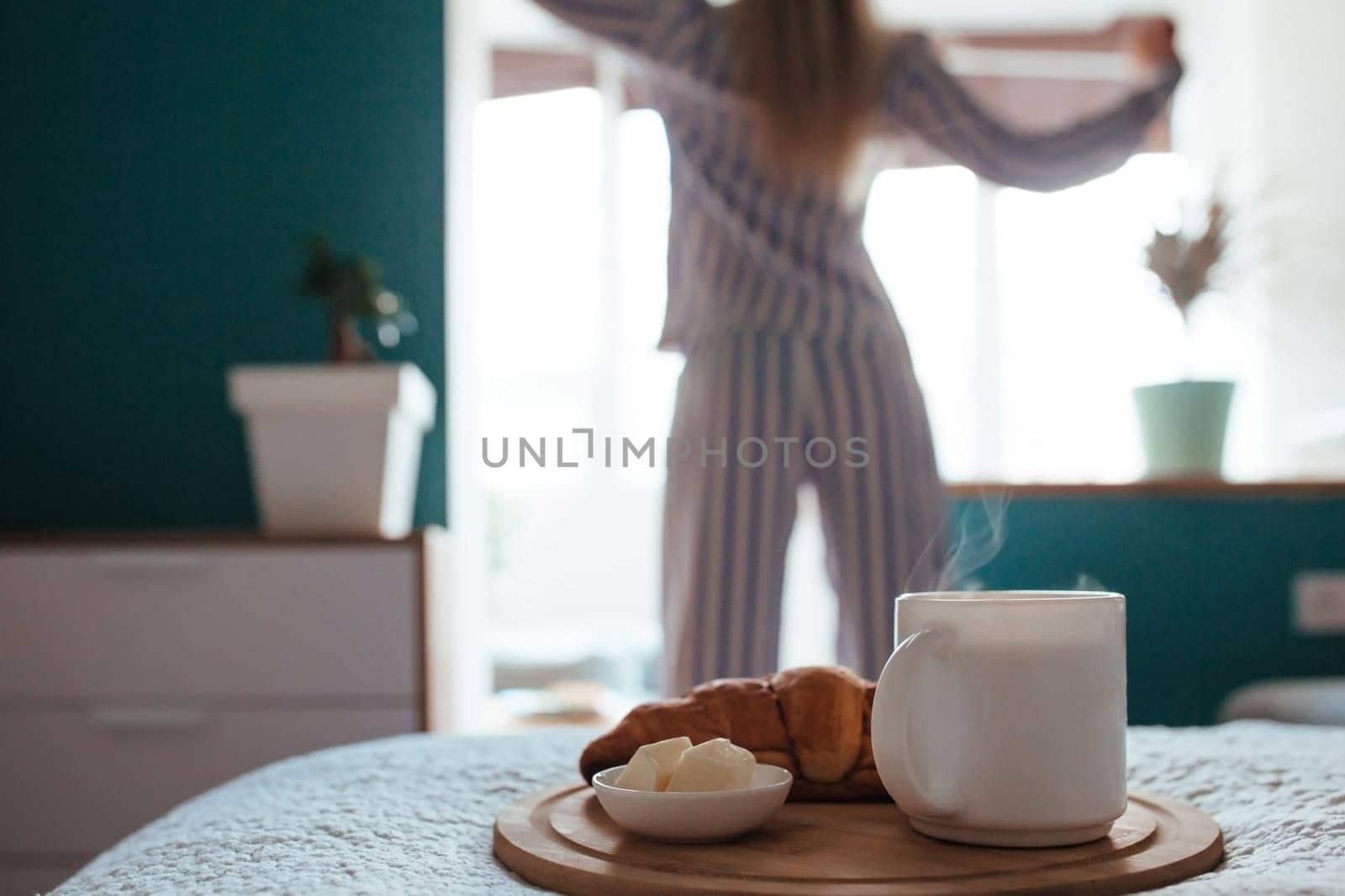 croissant and coffee in the foreground on the back of a girl in pyjamas. breakfast concept