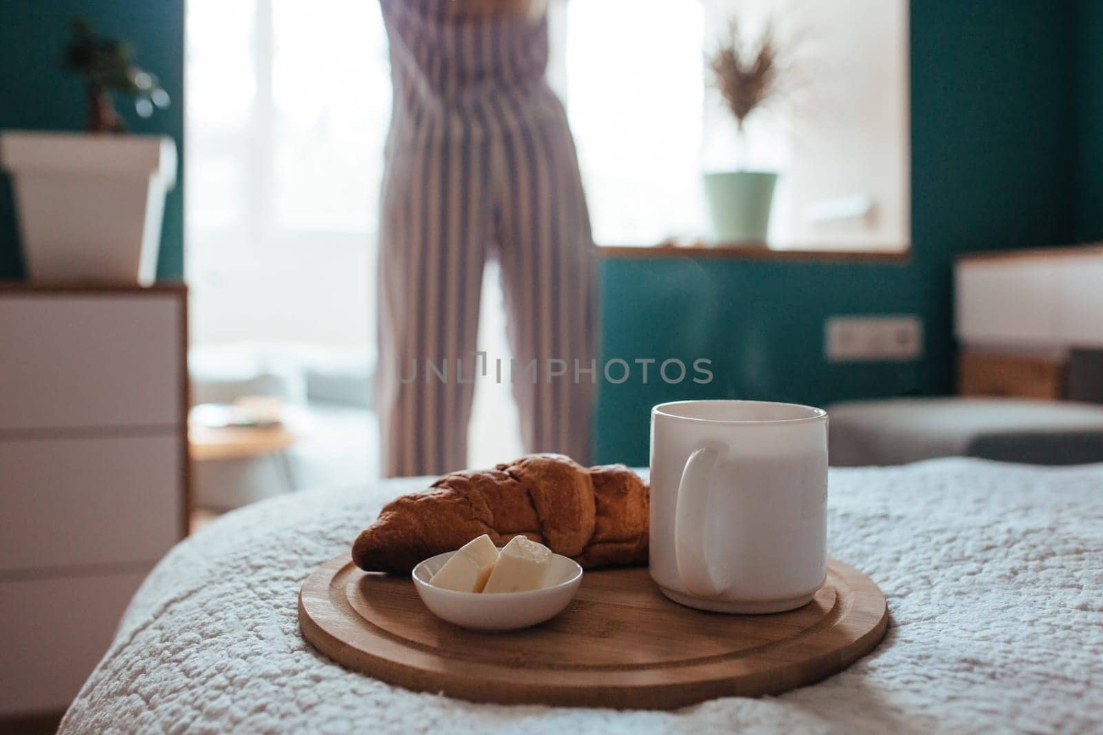 croissant and coffee in the foreground on the back of a girl in pyjamas. breakfast concept