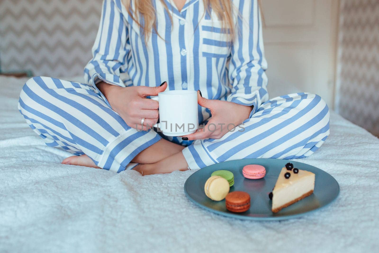 a woman in the morning drinks coffee and eats sweets cheesecake sweet macaroni . breakfast in bed concept