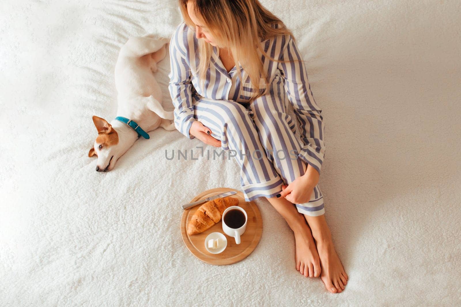 morning breakfast in bed croissant and coffee. next to her is a woman in pajamas . top view