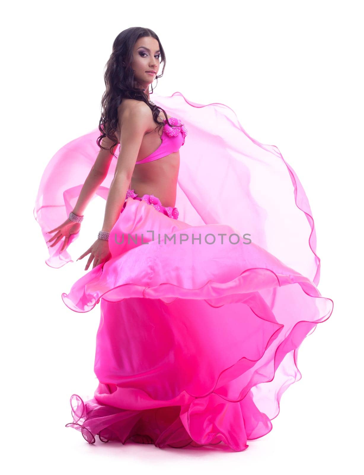 Full length portrait of dancer in pink costume performing oriental dance. Isolated on white