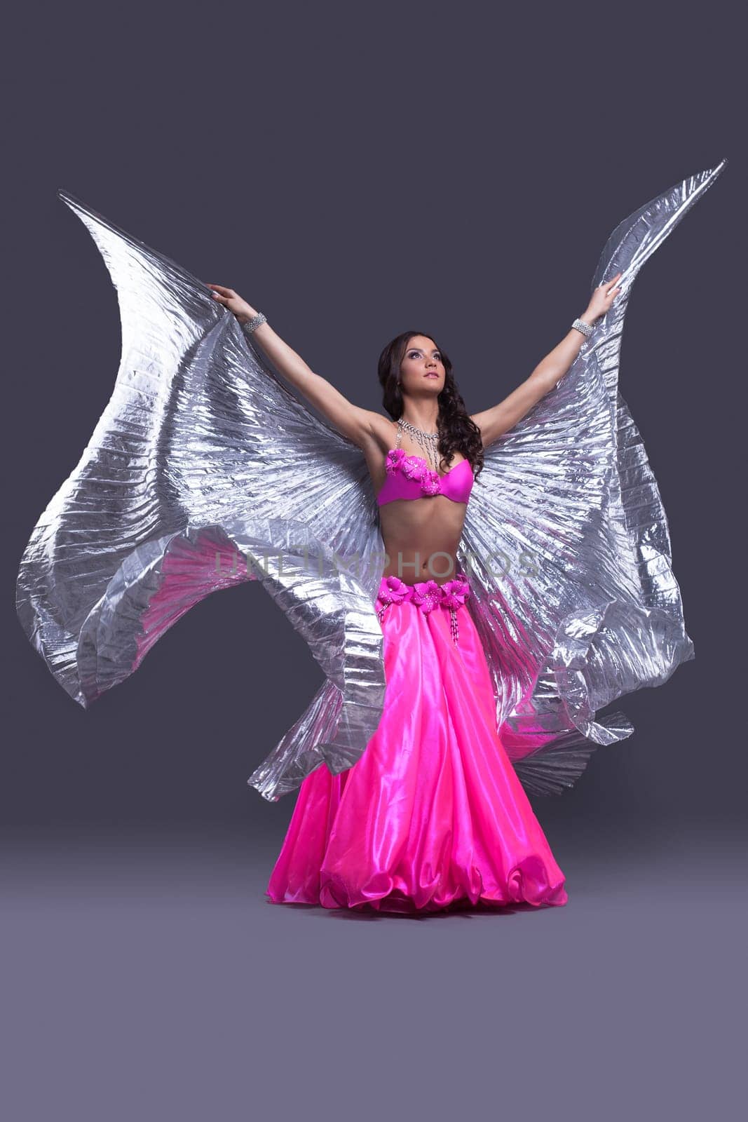 Full length portrait of beautiful dancer performing oriental dance with silver wings