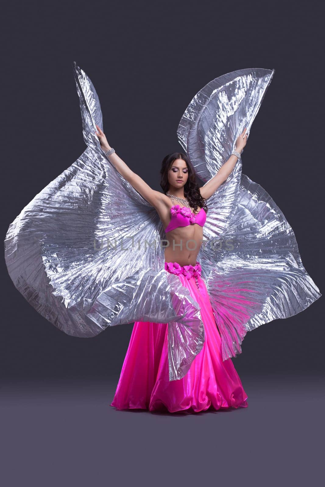 Full length portrait of beautiful dancer performing oriental dance with silver wings