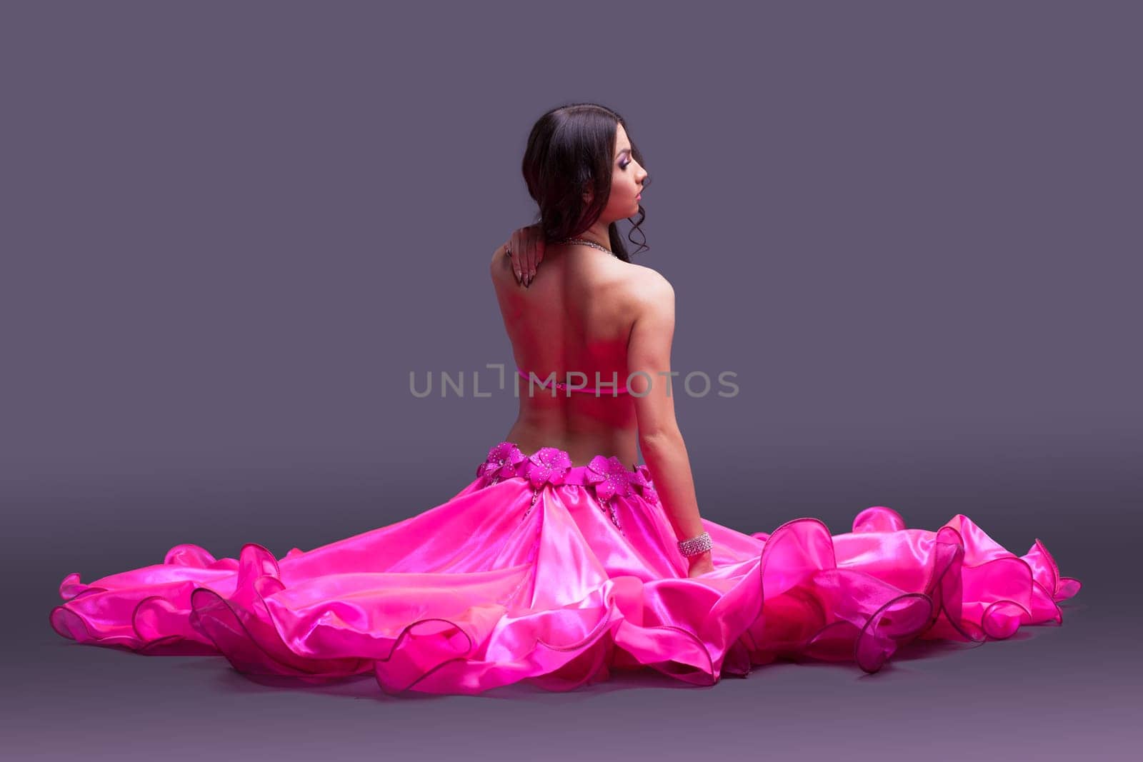 Studio portrait of dancer in pink costume sitting on floor