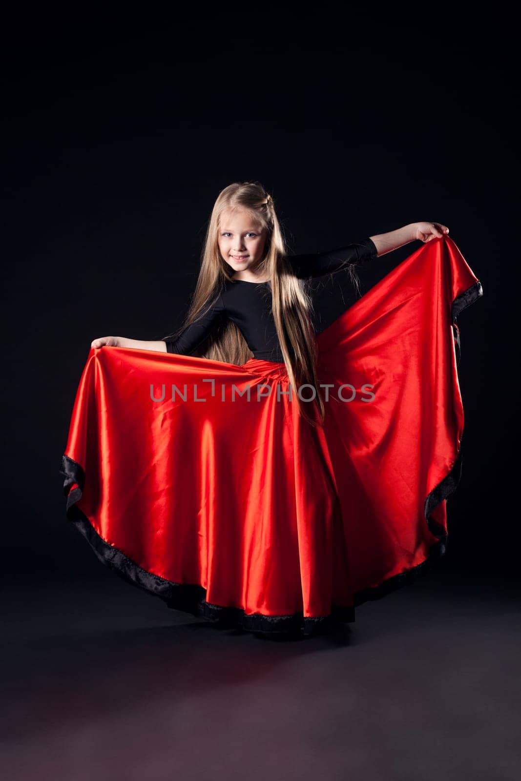 Full length portrait of Pretty little girl performing hispanic dance in dark
