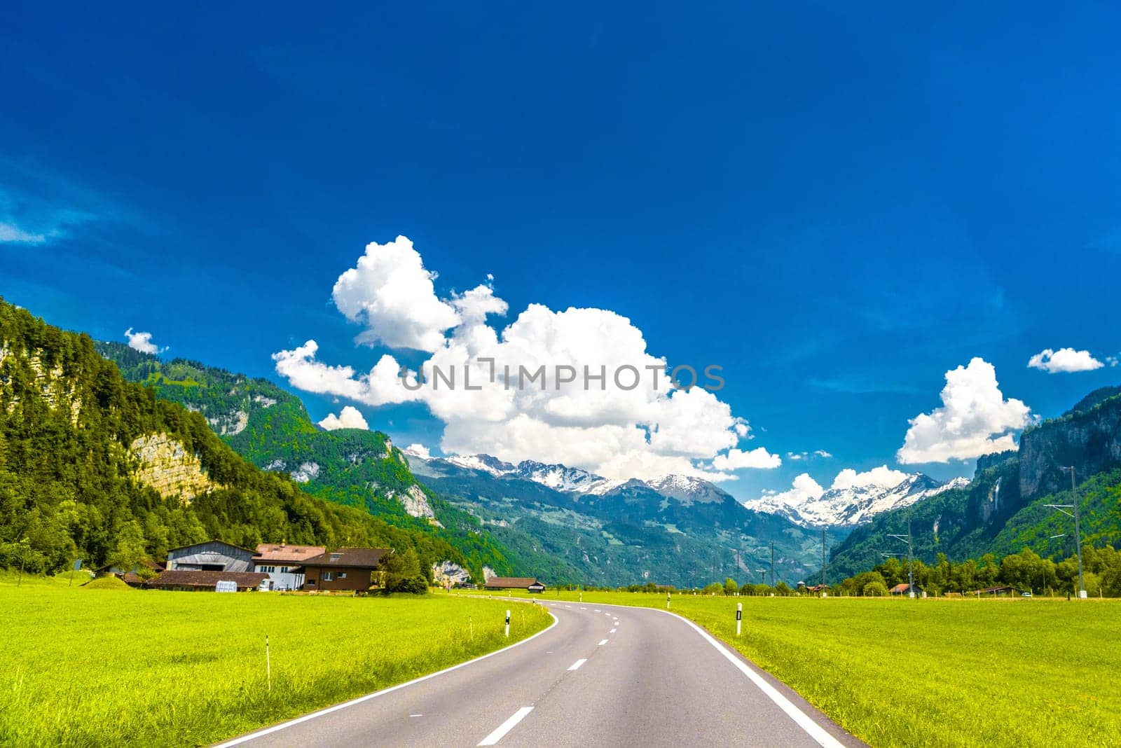 Asphalt road among green meadows, Brienz, Interlaken-Oberhasli, Bern Switzerland.