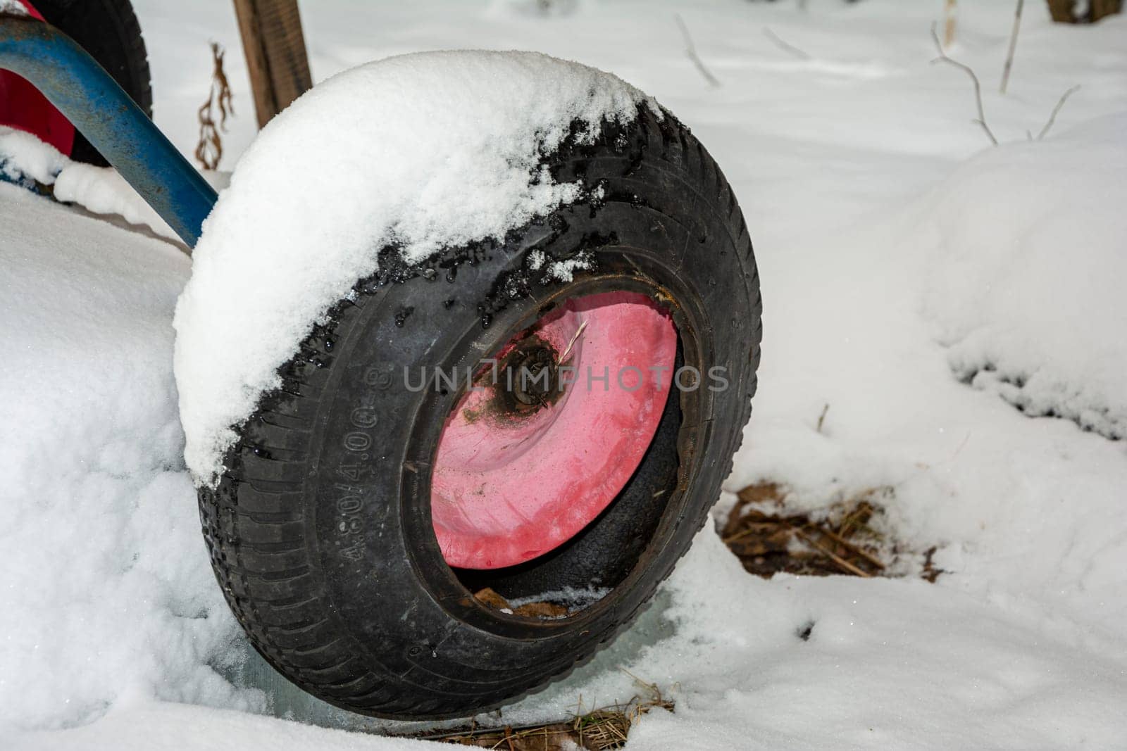 a deflated, damaged wheel from a garden wheelbarrow in the snow. High quality photo