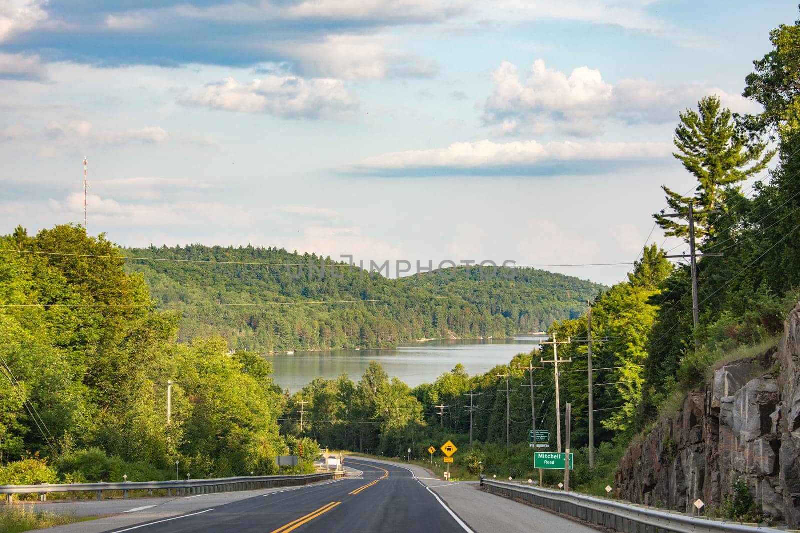 The road to a large lake surrounded on all sides by forests