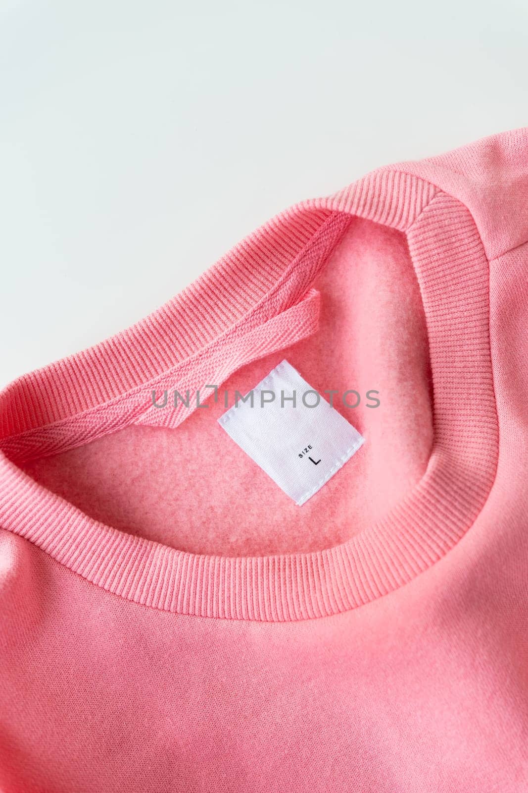 Clothing, fashion, shopping concept - closeup of a coral sweater tag. Place for inscription. Size L is written on the jacket
