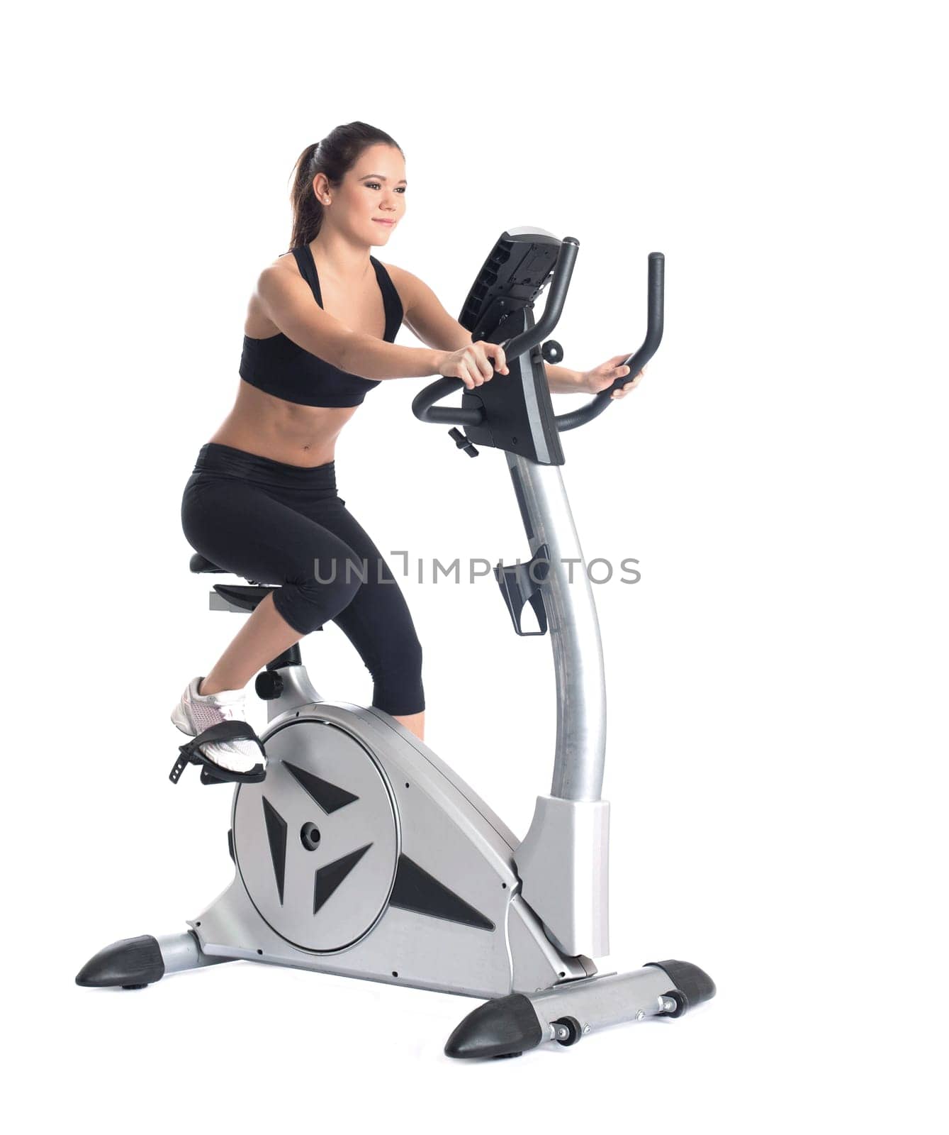 Young brunette woman on bike exerciser. Isolated on white