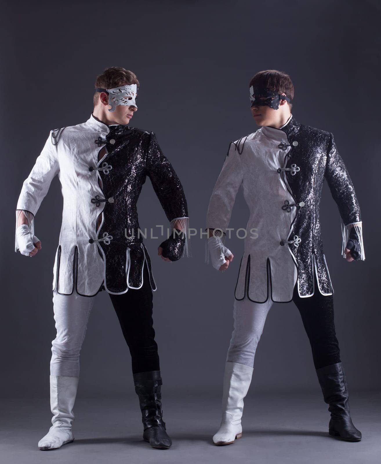 beautiful men posing in masquerade costumes, on gray background