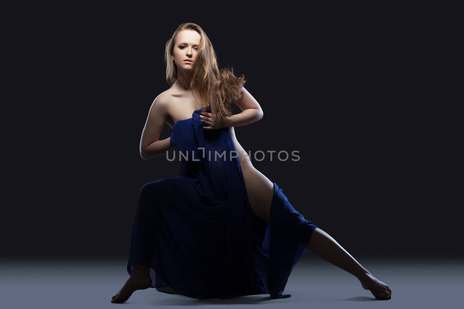 Full length portrait of young woman posing with blue fabric