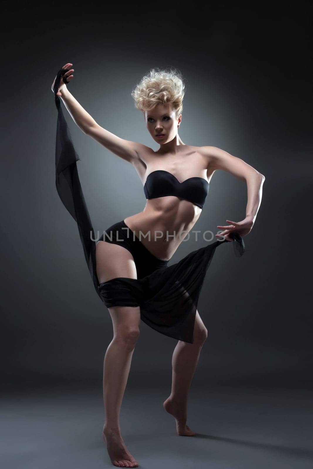 Sexy woman dancing with black fabric, on gray background