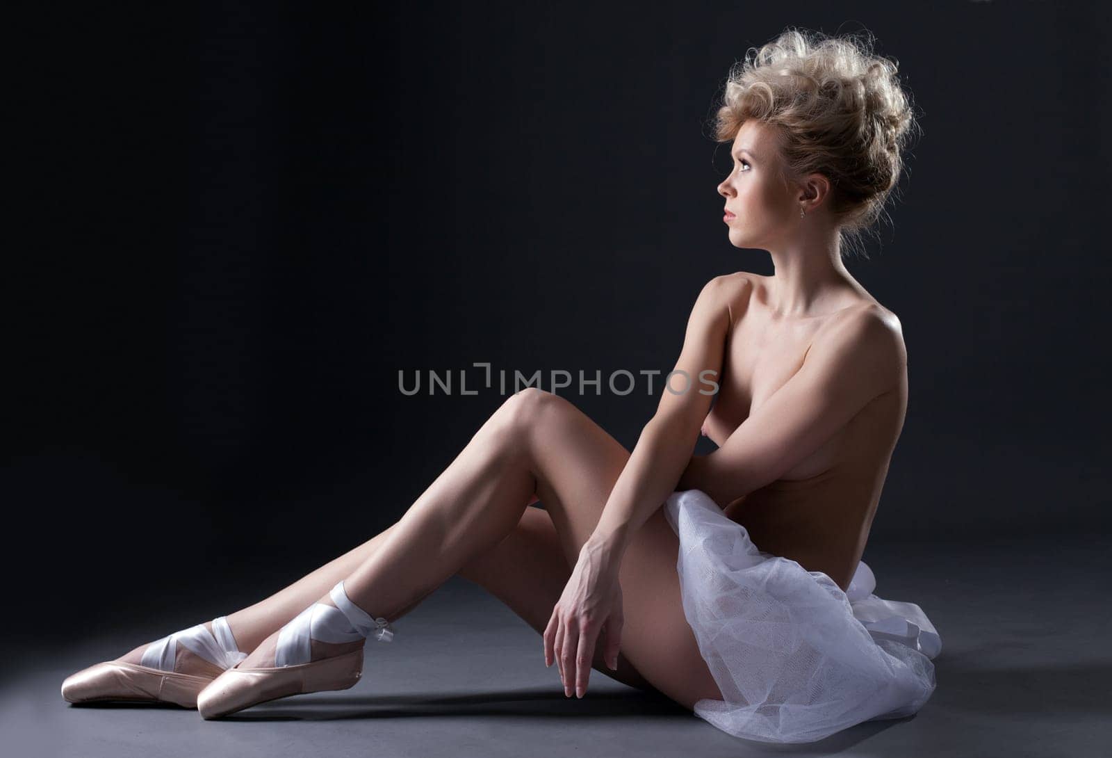 Beautiful topless blonde in ballet pointes over gray background