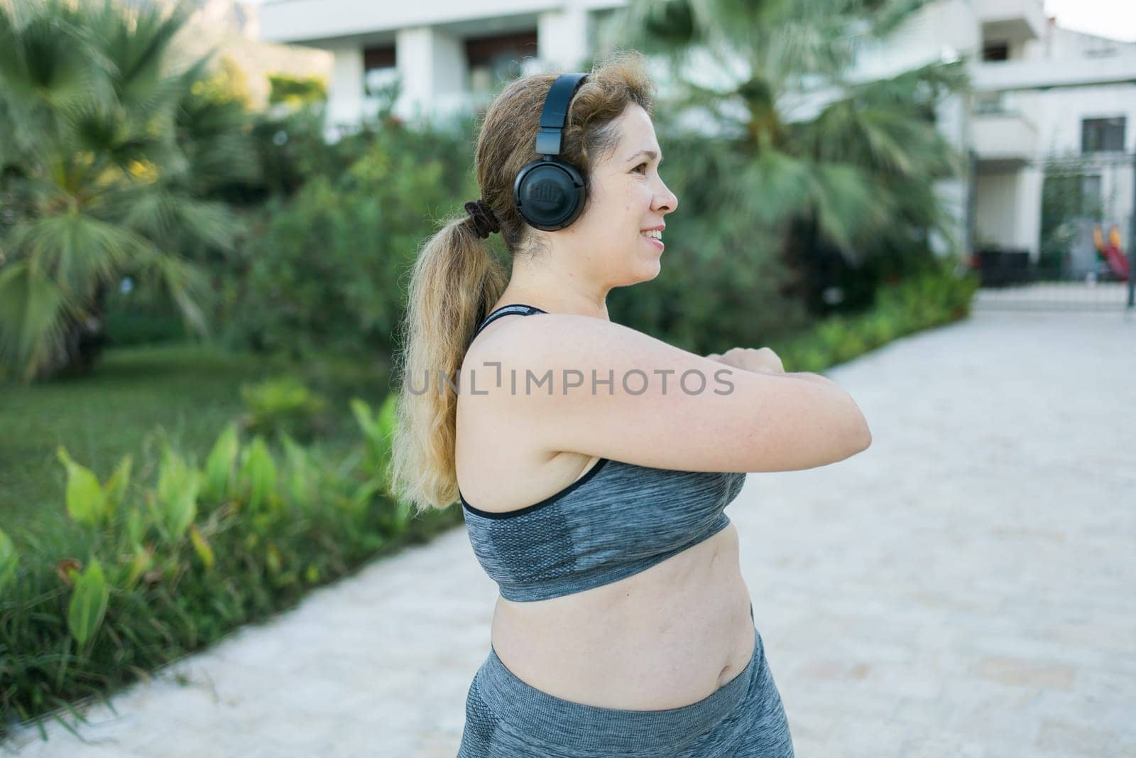 Young pretty smiling plus size woman in sporty top and leggings doing sport in summer outdoor