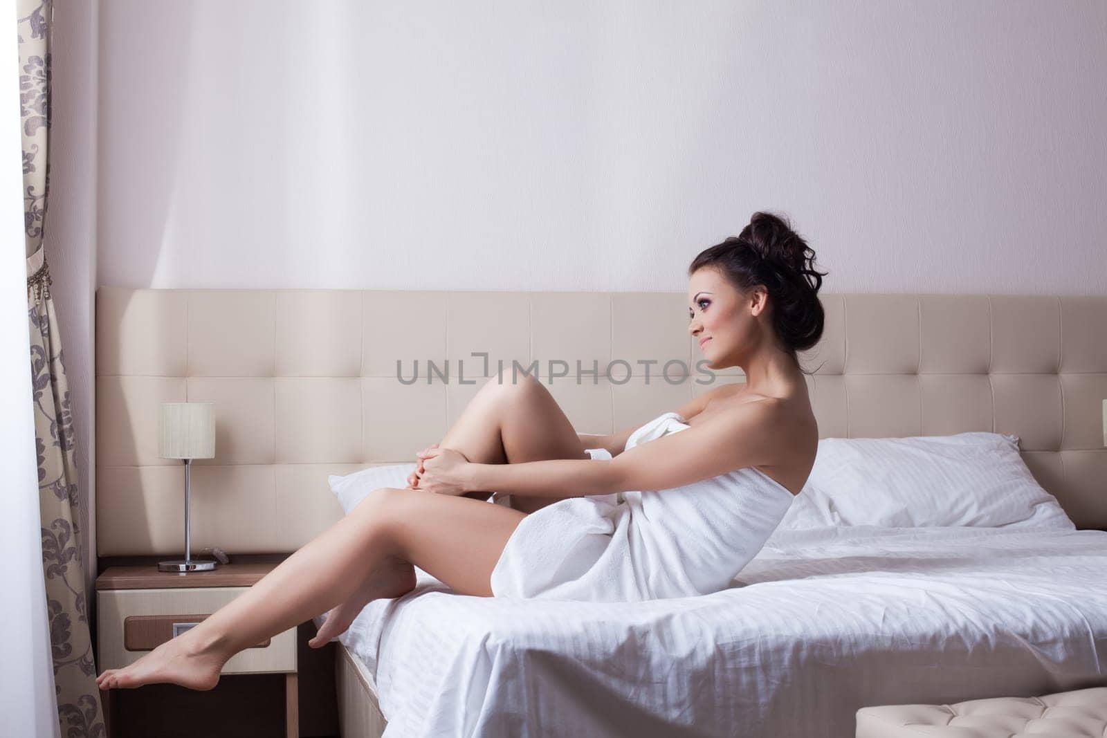 Smiling young girl sitting on bed in hotel room