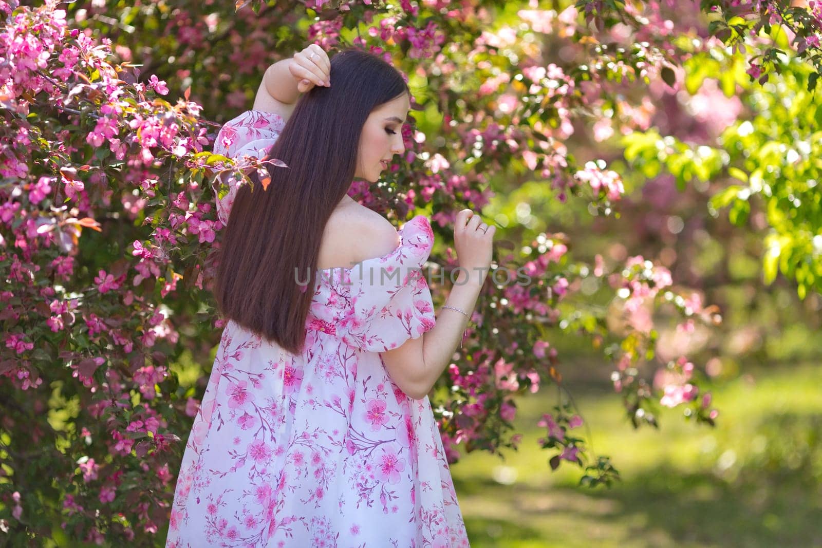 girl in a pink dress standing near pink blooming garden, rear view by Zakharova