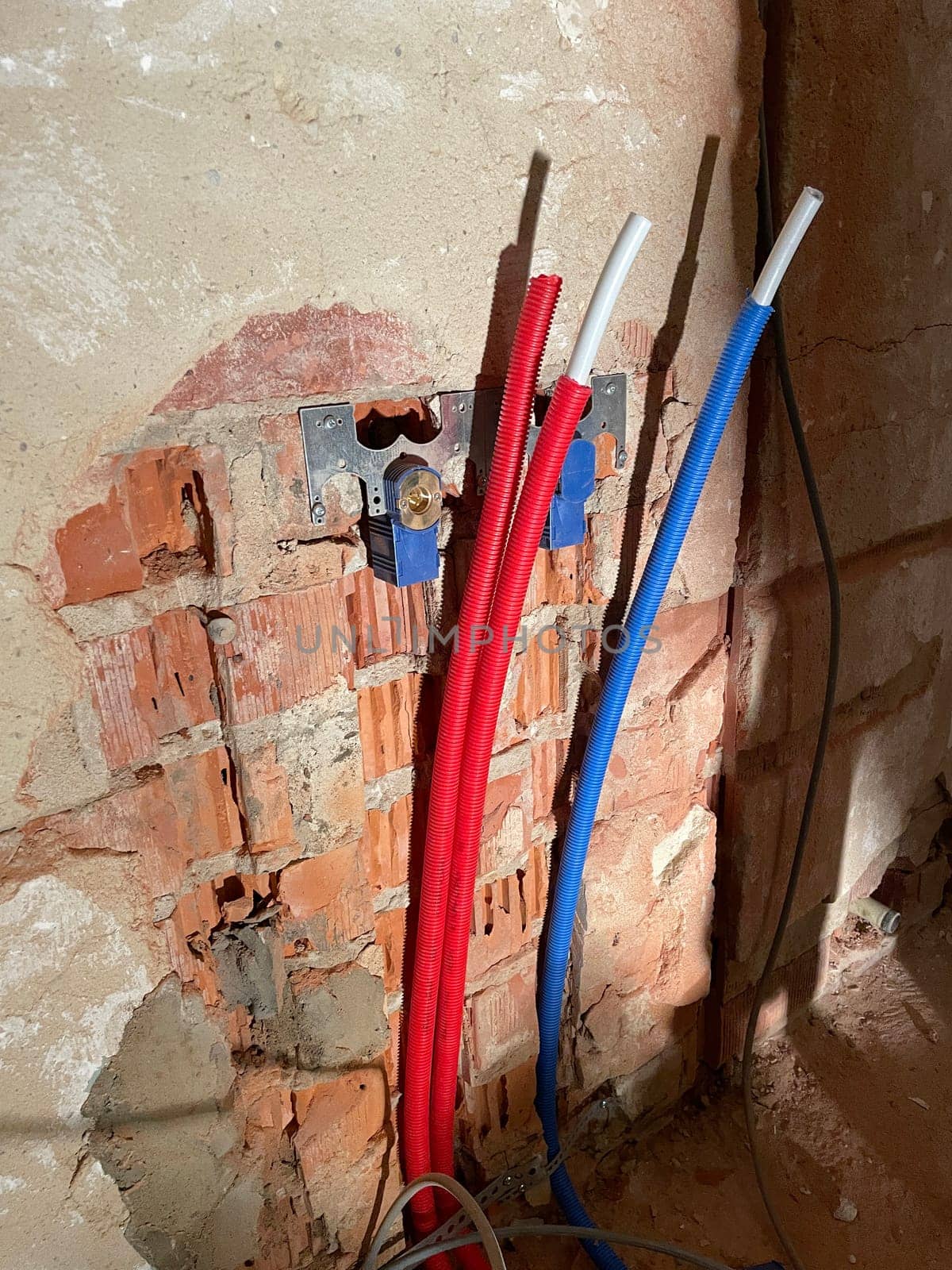 Red and blue corrugated pipes with wires come out of a a plasterboard wall. Distribution of wiring during repairs. Overheating of wires and cooling.High speed data transfer High quality photo