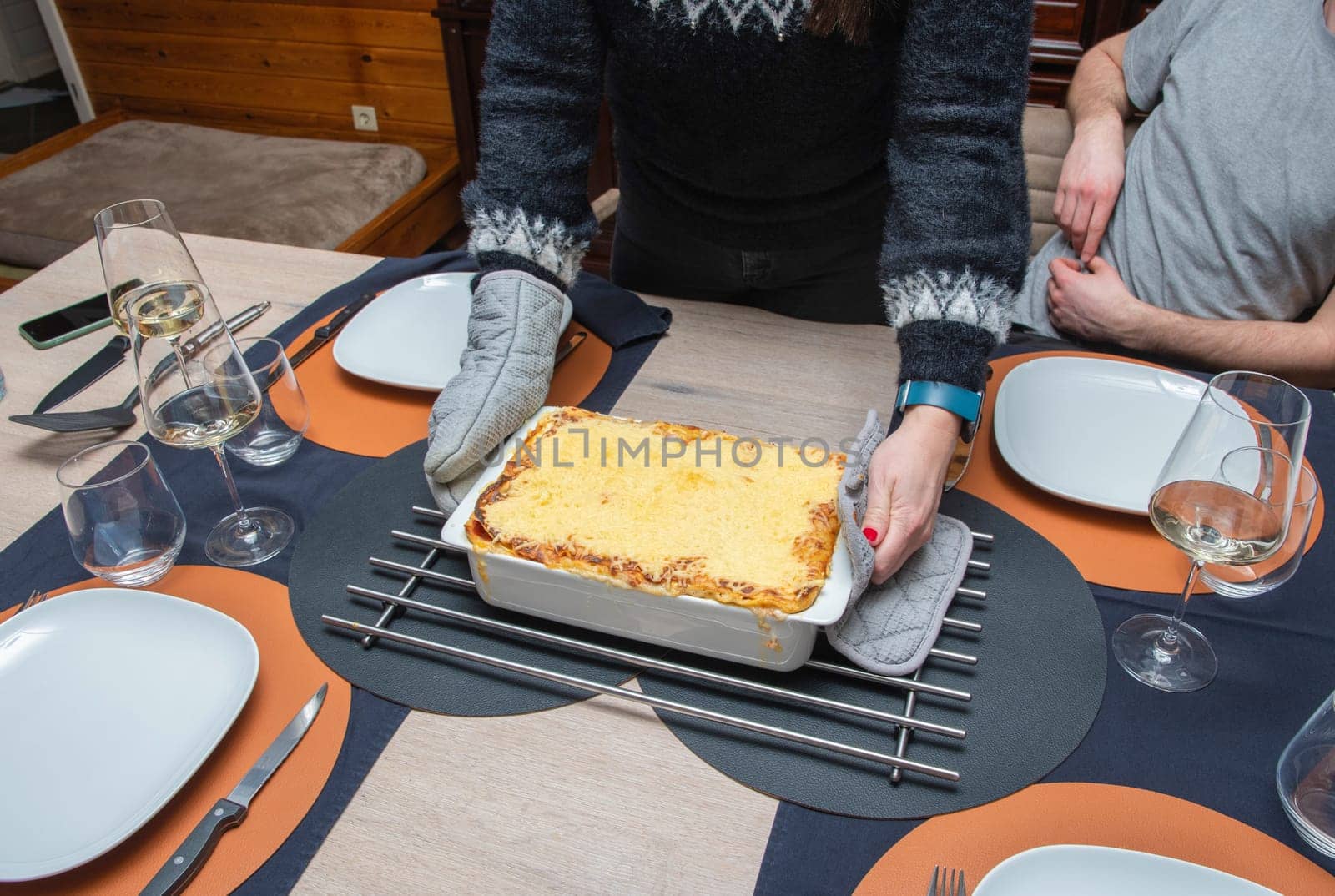Woman cut with knife hot tasty home baking lasagna in ceramic casserole dish by KaterinaDalemans
