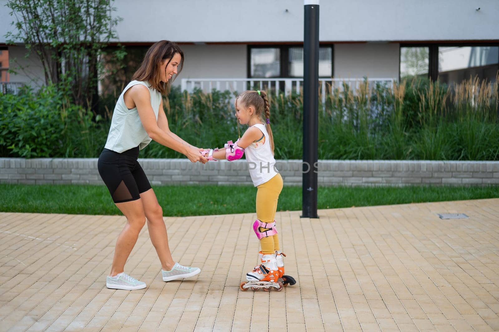 Mother helps daughter learn to roller skate