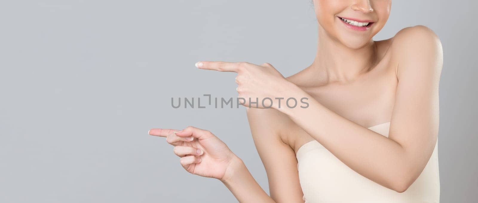 Closeup glamorous beautiful woman with perfect makeup clean skin pointing finger in copyspace isolated background. Promotion indicated by hand gesture concept for skincare product advertisement.