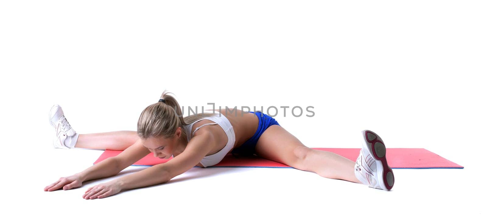 Athletic girl doing stretching exercises on mat by rivertime