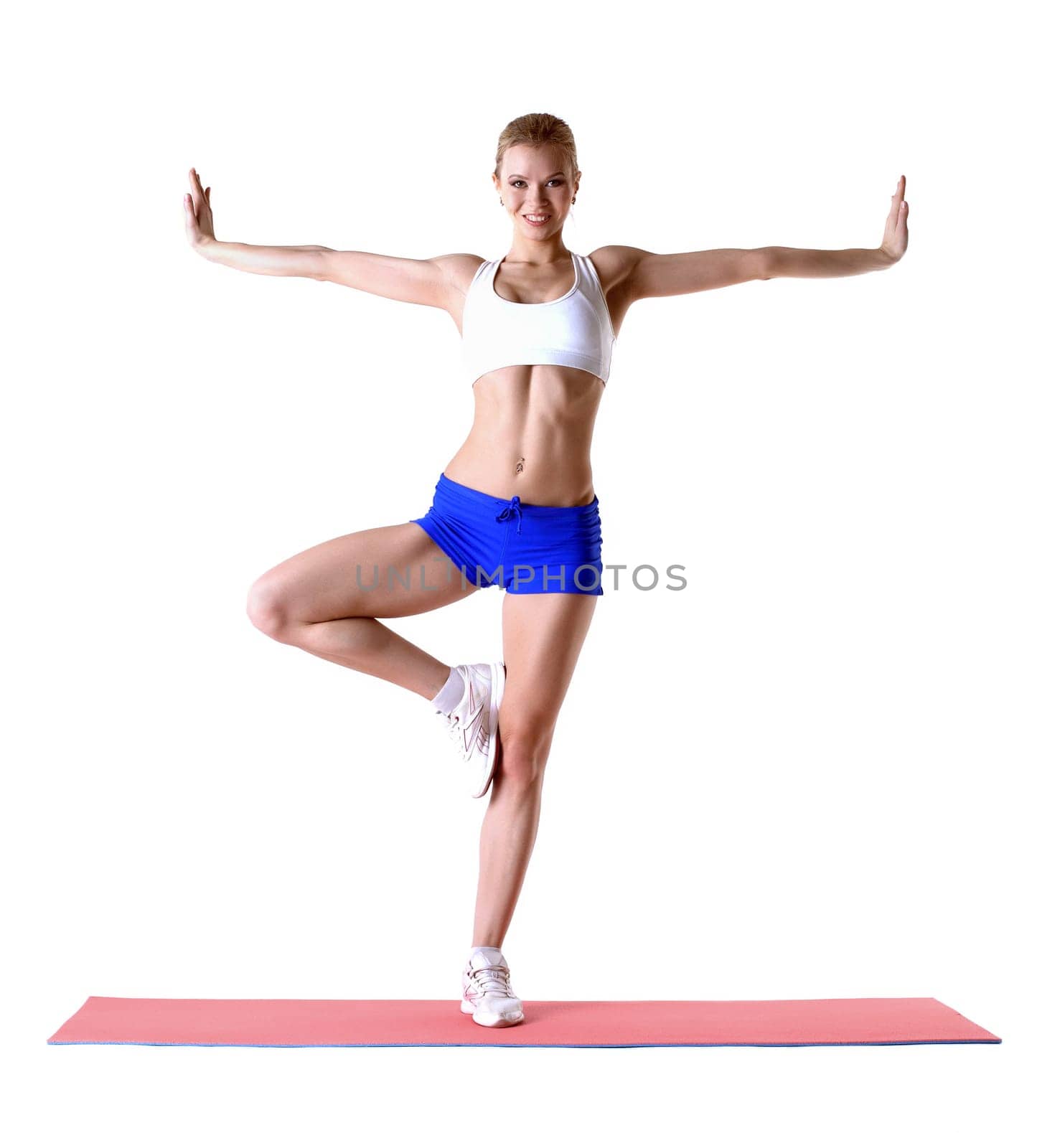 Attractive blonde posing on mat in studio, isolated over white background